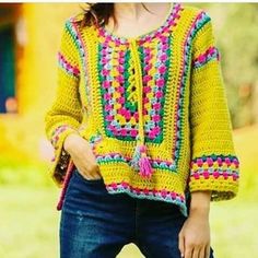 a woman wearing a yellow crocheted sweater and jeans