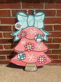 a pink christmas tree with blue bows on it's head is standing in front of a brick wall