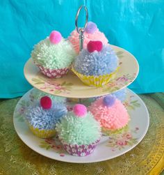 cupcakes with pom - poms are stacked on top of each other