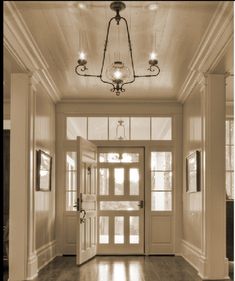 an empty hallway with two doors and chandelier hanging from the ceiling in sepia tone