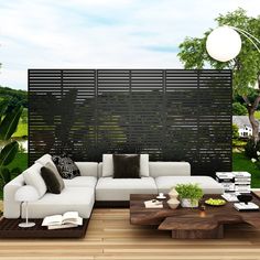 a modern living room with white couches and wooden tables in front of a privacy wall