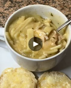 a bowl of macaroni and cheese next to two biscuits on a white plate