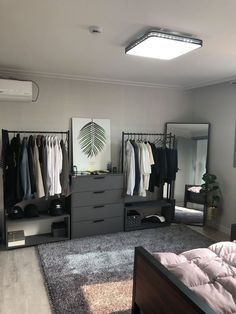 a bedroom with a bed, dresser and clothes on hangers in it's closet