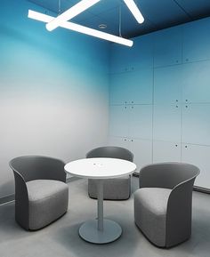 three chairs and a round table in an office setting with blue paint on the walls