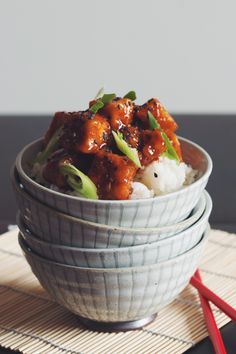 three bowls filled with food sitting on top of a bamboo place mat next to each other