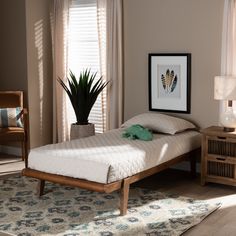 a bed sitting next to a window in a bedroom on top of a wooden floor