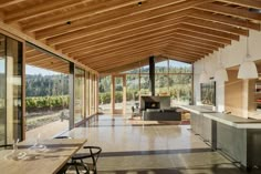 an open kitchen and dining area in a house with large windows, wood ceilinging and floor to ceiling glass walls