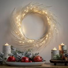 a wreath with candles and christmas decorations on a table