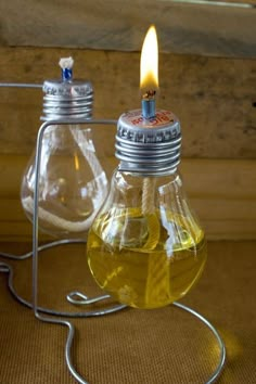 two light bulbs with oil in them sitting on a table next to a wire holder