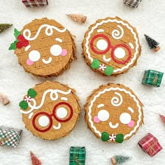 four decorated cookies sitting on top of a white table next to christmas presents and decorations