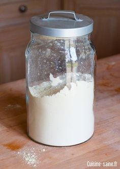 a glass jar filled with flour sitting on top of a wooden table