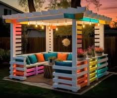 an outdoor seating area made out of pallet wood with lights on the top and bottom