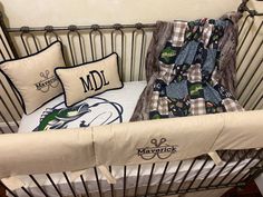 a baby crib with some pillows and blankets on it's sides, next to a pillow that says mdl