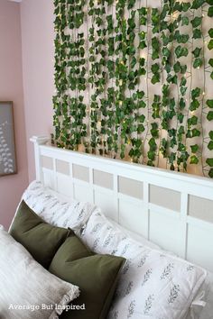 a bed with white sheets and green plants on the wall