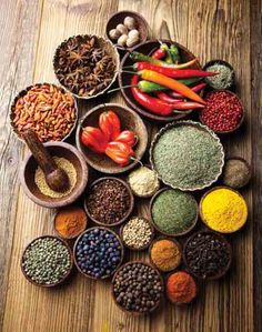 various spices and seasonings in bowls on a wooden table with peppers, chilies, garlic, pepper paste, etc