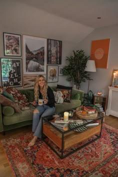 a woman sitting on top of a green couch in a living room next to a coffee table