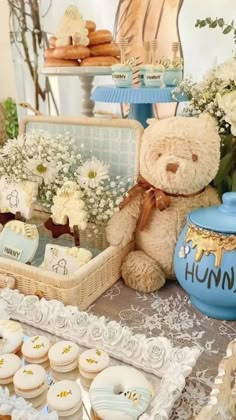 a teddy bear sitting next to a blue vase filled with flowers and cupcakes