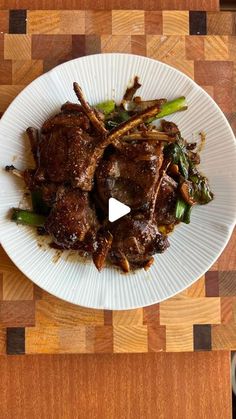 a white plate topped with meat and veggies on top of a wooden table