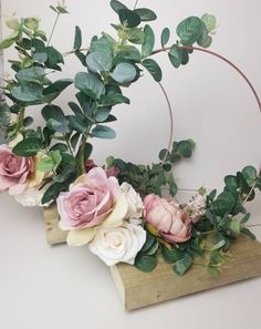 some pink and white flowers sitting on top of a piece of wood with greenery