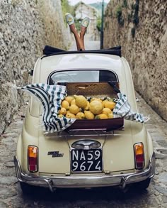 an old car with a basket full of lemons on the back in a narrow alleyway