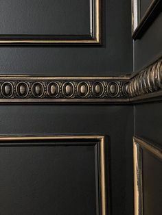 a close up of a black door with gold trimmings on the bottom half