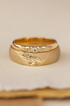 two gold wedding bands sitting on top of each other