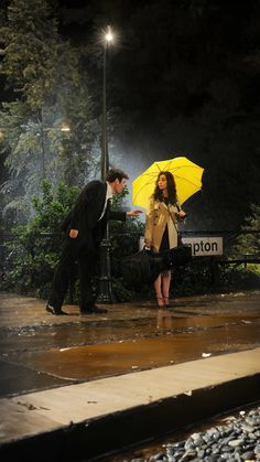 a man and woman standing in the rain under an umbrella