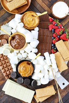 an assortment of desserts and marshmallows arranged on a wooden table top