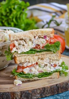 a sandwich cut in half sitting on top of a cutting board next to a bowl of salad