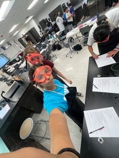 two children wearing red goggles in an office setting