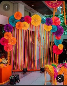 there are many colorful paper umbrellas hanging from the ceiling and decorations on the wall