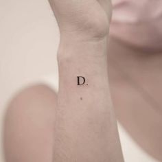 a woman's wrist tattoo with the letter d on her left hand, in black ink