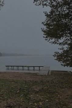 an empty dock in the middle of a body of water on a foggy day