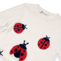 a white sweater with red and black ladybugs on it