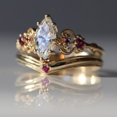 two gold wedding rings with an oval cut diamond surrounded by rubish garnets