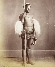 an old photo of a native american man with feathers on his head and holding a pole