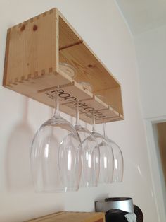 three wine glasses hanging from a wooden shelf