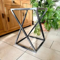 a metal table sitting on top of a kitchen floor next to a potted plant