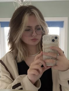 a woman taking a selfie in front of a mirror with her cell phone up to her ear