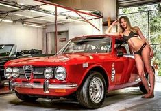 a beautiful woman standing next to a red car