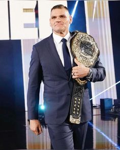 a man in a suit and tie holding a wrestling belt