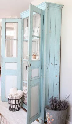 an old blue cabinet in the corner of a room next to a potted plant