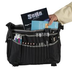 a person holding a black bag filled with pens, pencils and other office supplies