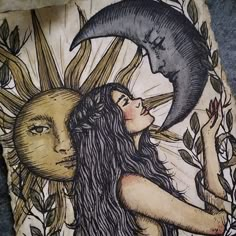 a woman with long hair holding a sun and moon above her head on a piece of wood