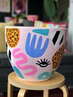 a colorful bowl sitting on top of a wooden stool