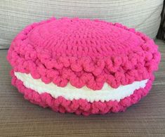 a pink and white knitted cushion sitting on top of a couch