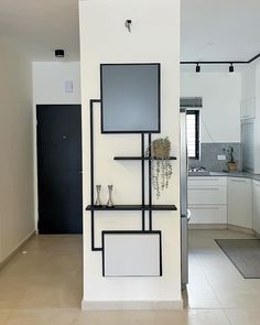 a white and black wall in a kitchen with shelves on the wall, vases sitting on top of each shelf