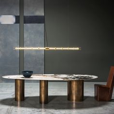 a modern dining table with two chairs and a bowl on it, in front of a gray wall