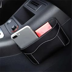 a cell phone in a black leather case on a car seat with an external charger attached to it