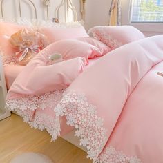 pink bedding with white lace trim on the edges and pillow cases in a bedroom